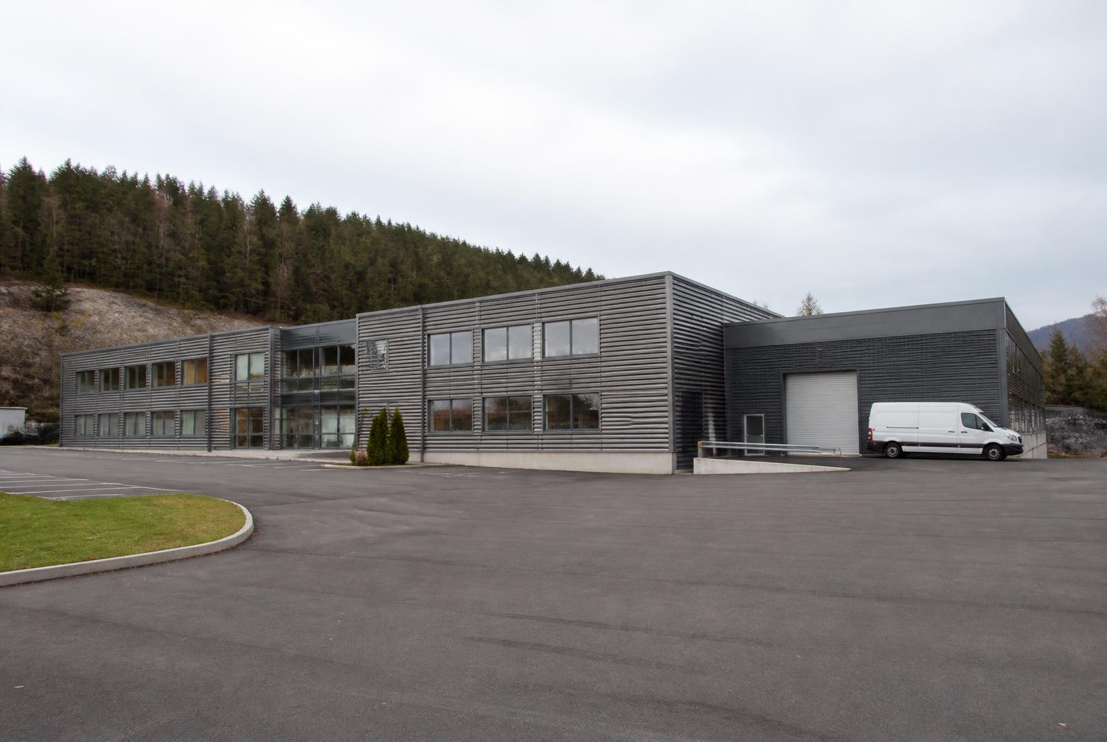Næringsbygg med parkeringsareal og port for varelevering i et biltilgjengelig område, likt Holmen- og Billingstad-aksen i Asker