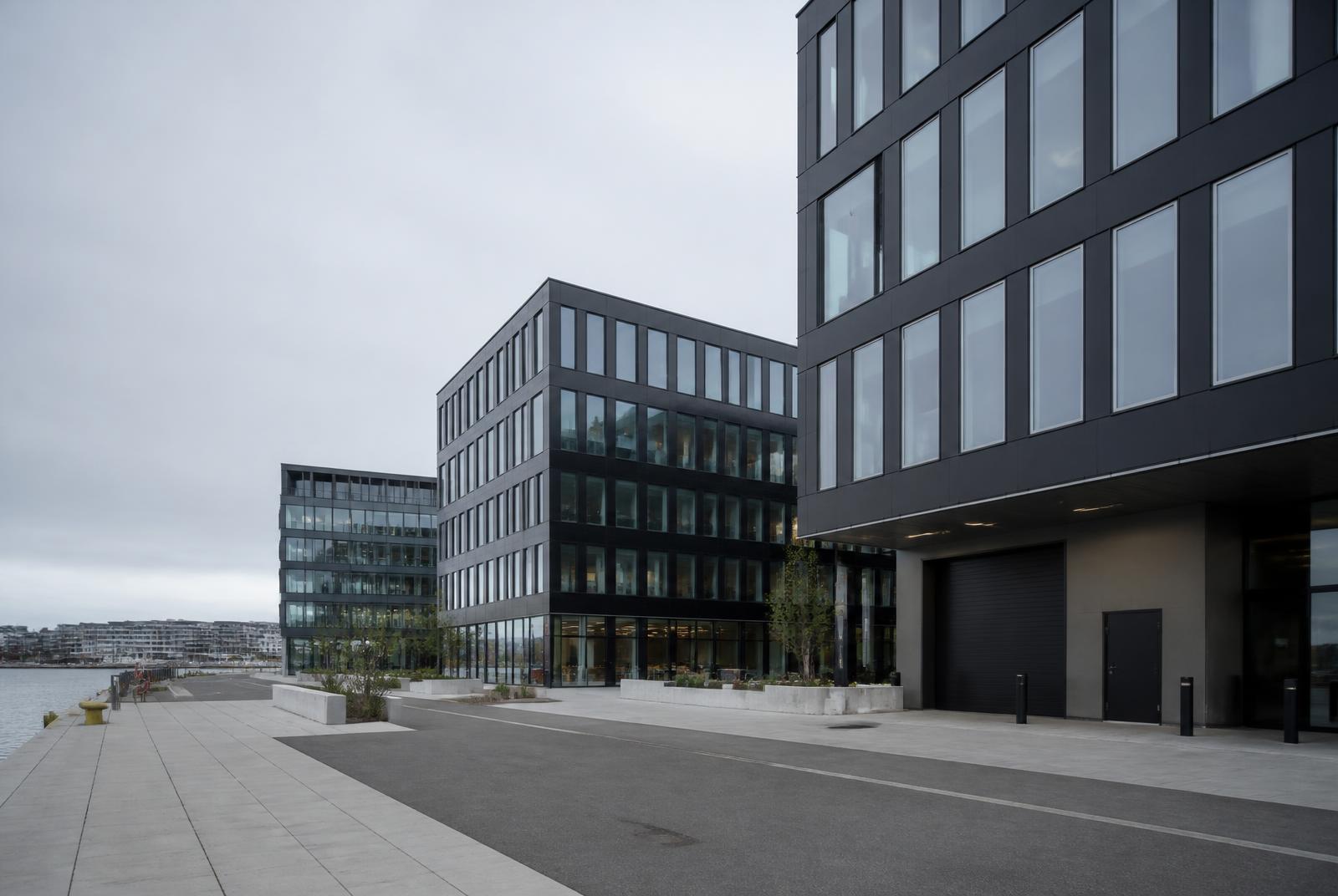Nyere kontorbygg i moderne byutviklingsområde ved vannet med vareinngang, som illustrasjon til kontorflytting på Værste